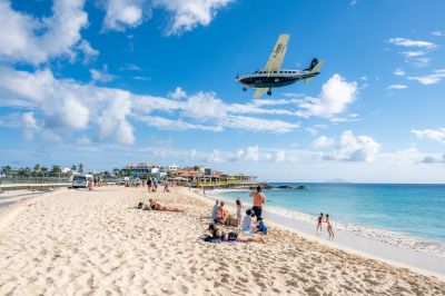 Maho Beach with people relaxing and small plane landing