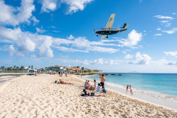 Maho Beach with people relaxing and small plane landing